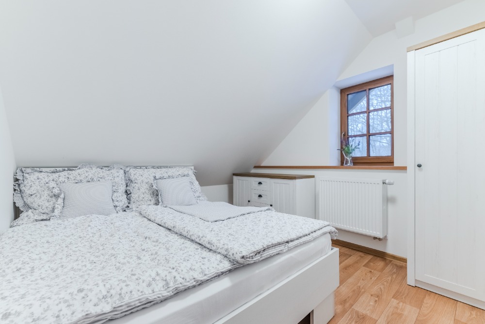 Podkrovní ložnice s dřevěným oknem